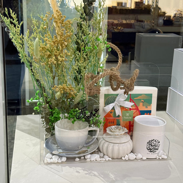 Decorative table setting with flowers, candles, and a teapot on a reflective surface.