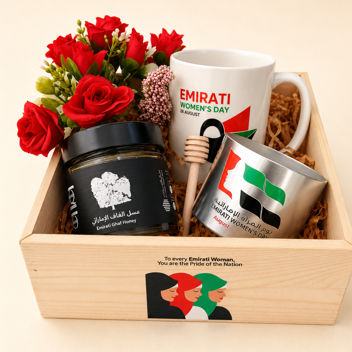 A curated gift basket for an Emirati woman, presented in a light wood box with red roses, a jar of Emirati Gold Honey, a white ceramic mug celebrating Women's Day, a wooden honey dipper, and a silver tumbler with the UAE flag.