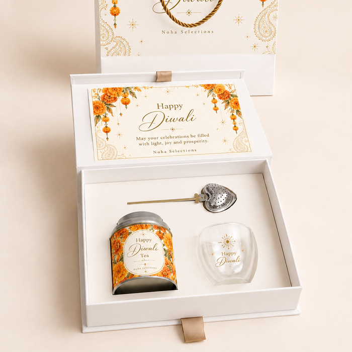 A luxury open white and gold Noha Selections Diwali gift box featuring a branded tea tin, glass teacup, gold heart tea infuser, and festive greeting card.