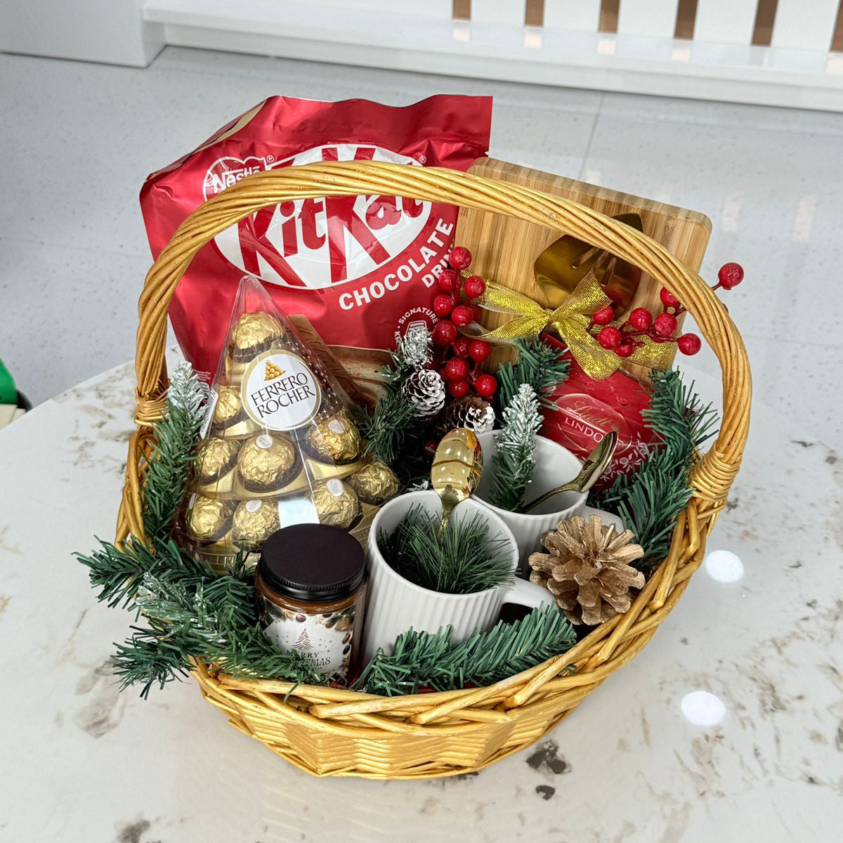 Gift basket with Christmas decorations and KitKat chocolate on a white surface