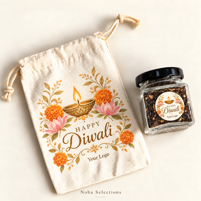 A natural fabric drawstring gift pouch with a custom "Happy Diwali" Noha Selections tag, styled alongside a small glass treat jar with a gold lid, a traditional golden diya, and scattered marigold petals.