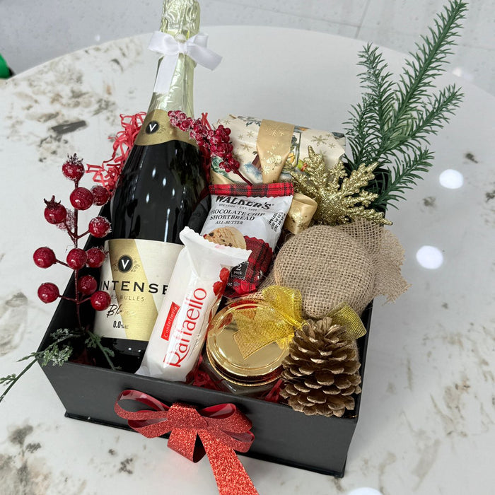 Gift basket with champagne, snacks, and decorative items on a marble surface