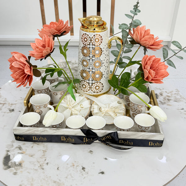 Decorative setting with flowers, candles, and a book on a marble surface.