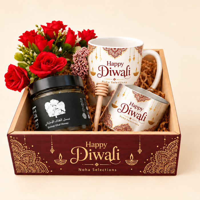 A Diwali gift basket from Naha Selections featuring a white ceramic mug, a tin of chai, a jar of honey, a wooden honey dipper, red roses, and a decorative box with gold Diwali designs and the text 'Happy Diwali'.