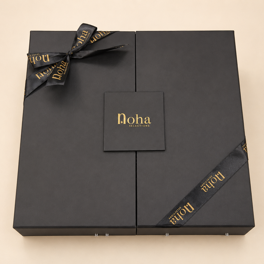 A black rectangular gift box with a bow and ribbon, featuring the brand name 'Noha Marrakech' printed in gold on the front and along the ribbon, set against a light beige background.