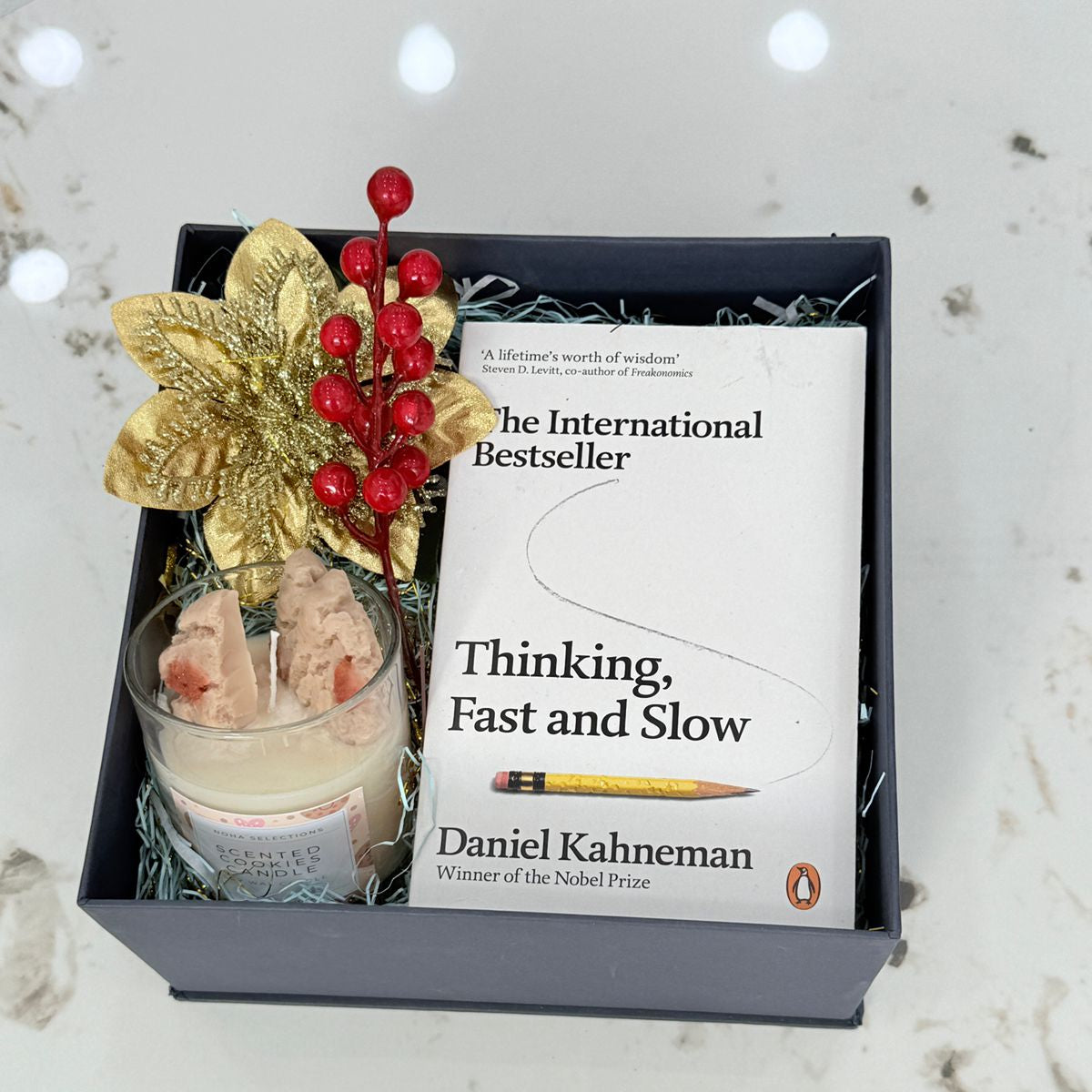 Book 'Thinking, Fast and Slow' by Daniel Kahneman with decorative elements in a box on a marble surface.