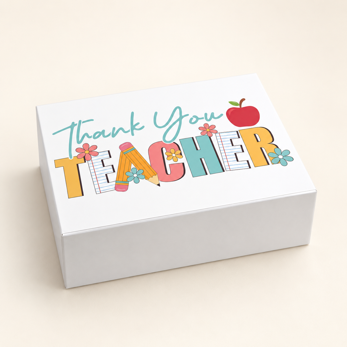 An open white gift box contains a printed teacher mug and two red apple-shaped items, 