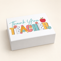 An open white gift box contains a printed teacher mug and two red apple-shaped items, 
