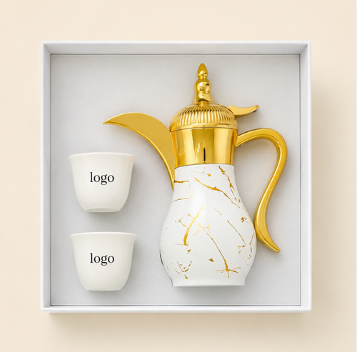 A luxury coffee set presented in a white gift box, featuring a white ceramic coffee pot with gold marble veining and shiny gold metallic accents, accompanied by two small white cups with placeholder logos.