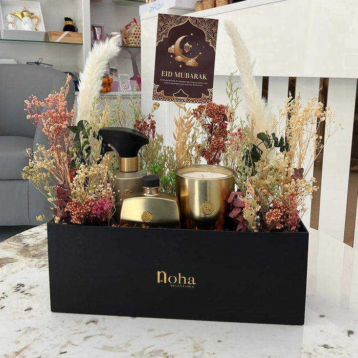 Decorative gift box with 'Eid Mubarak' card, gold containers, and pampas grass in a store setting. rituals
