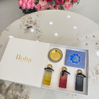 Set of three perfume bottles with a decorative box labeled  on a marble surface with flowers in the background.