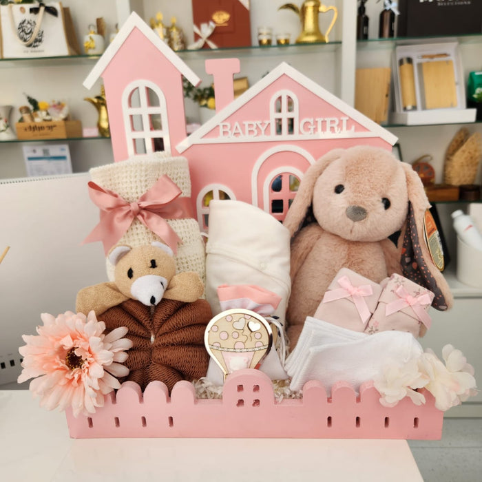 Baby girl-themed decorative set with teddy bears, flowers, and a house-shaped box on a shelf.