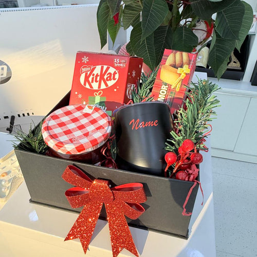 Gift basket with a mug, KitKat bars, and other items on a table.