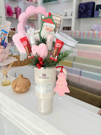 Decorative stanley cup with Christmas-themed packaging on a shelf